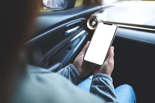 Image maquette d'une femme tenant et utilisant un téléphone portable avec écran vide dans la voiture