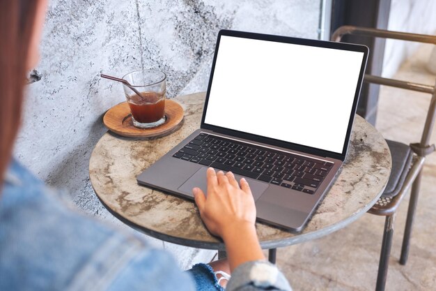 Image maquette d'une femme touchant le pavé tactile d'un ordinateur portable avec un écran de bureau blanc vierge sur la table