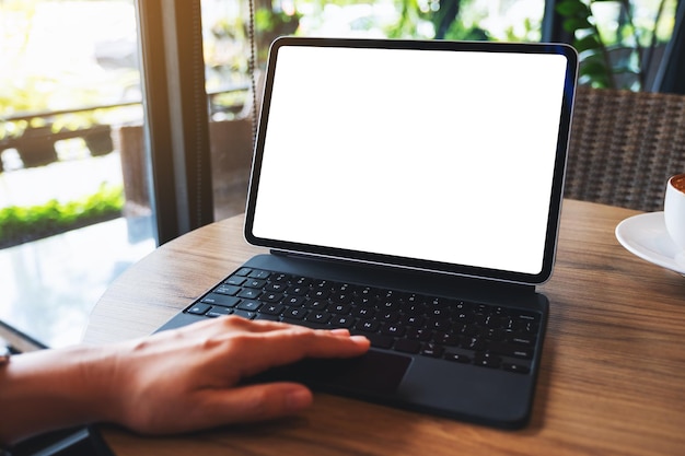 Image maquette d'une femme touchant le pavé tactile de la tablette avec un écran de bureau blanc vierge comme un ordinateur avec une tasse de café sur la table