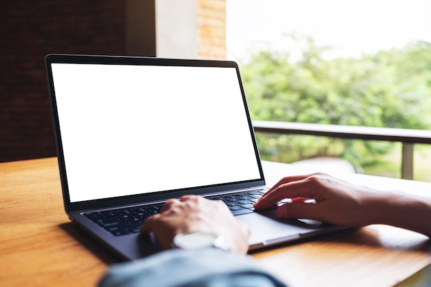 Image maquette d'une femme utilisant et tapant sur un clavier d'ordinateur portable avec un écran de bureau blanc vierge sur une table en bois