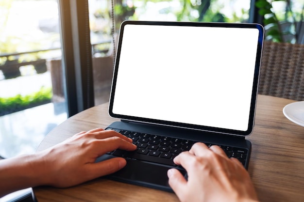 Image maquette d'une femme utilisant et tapant sur le clavier de la tablette avec un écran de bureau blanc vierge comme un ordinateur sur la table