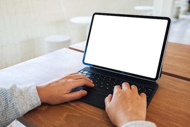 Image maquette d'une femme utilisant et tapant sur le clavier de la tablette avec un écran de bureau blanc vierge comme un ordinateur sur la table