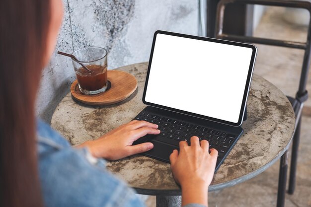 Image maquette d'une femme utilisant et tapant sur le clavier de la tablette avec un écran de bureau blanc vierge comme un ordinateur sur la table