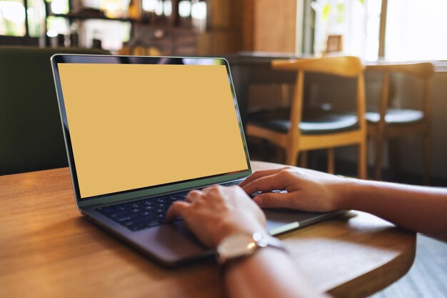 Image maquette d'une femme utilisant et tapant sur un ordinateur portable avec un écran de bureau blanc vierge au café