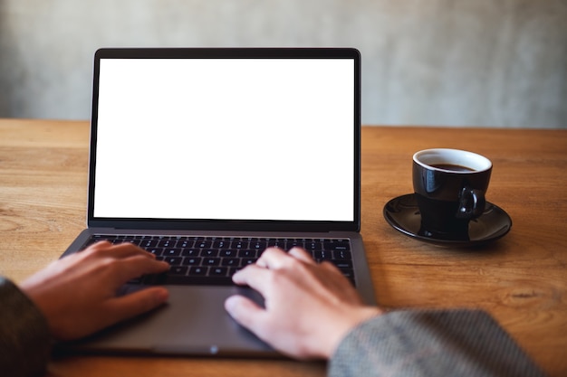 Image maquette d'une femme utilisant et tapant sur un ordinateur portable avec un écran de bureau blanc vierge avec une tasse de café sur une table en bois