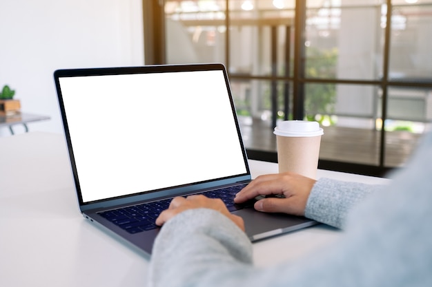 Image maquette d'une femme utilisant et tapant sur un ordinateur portable avec un écran de bureau blanc vierge avec une tasse de café sur la table