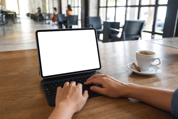 Image maquette d'une femme utilisant et tapant sur une tablette numérique avec un écran de bureau blanc vierge dans un café