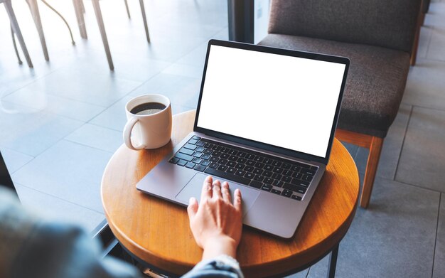 Image maquette d'une femme utilisant et touchant le pavé tactile d'un ordinateur portable avec un écran de bureau blanc vierge dans un café