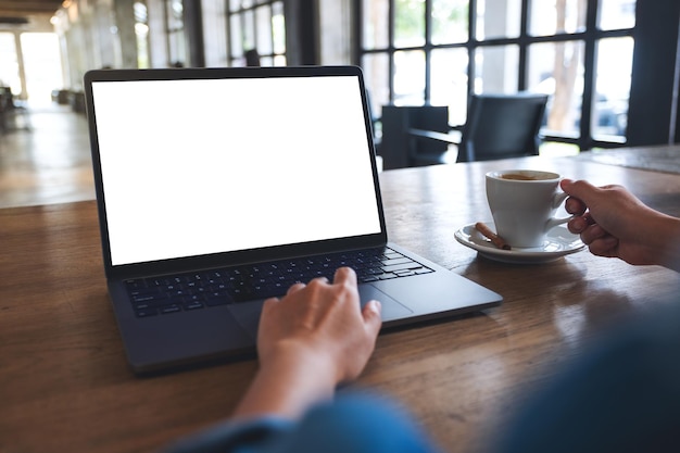 Image maquette d'une femme utilisant et touchant le pavé tactile d'un ordinateur portable avec un écran de bureau blanc vierge tout en buvant du café