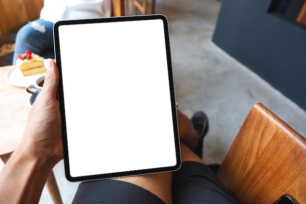 Image maquette d'un homme tenant une tablette numérique avec un écran de bureau blanc vierge dans un café