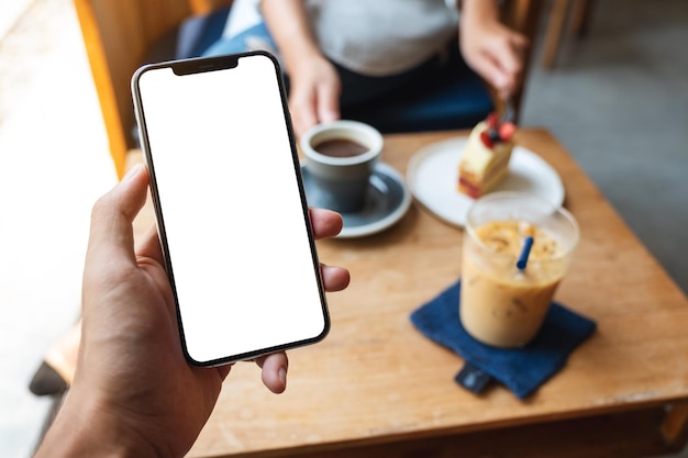 Image maquette d'un homme tenant un téléphone portable avec un écran blanc vierge dans un café