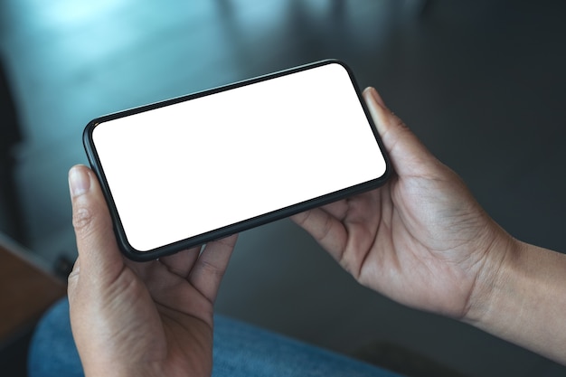 Image de maquette d'une main de femme tenant un téléphone mobile noir avec écran de bureau vide horizontalement