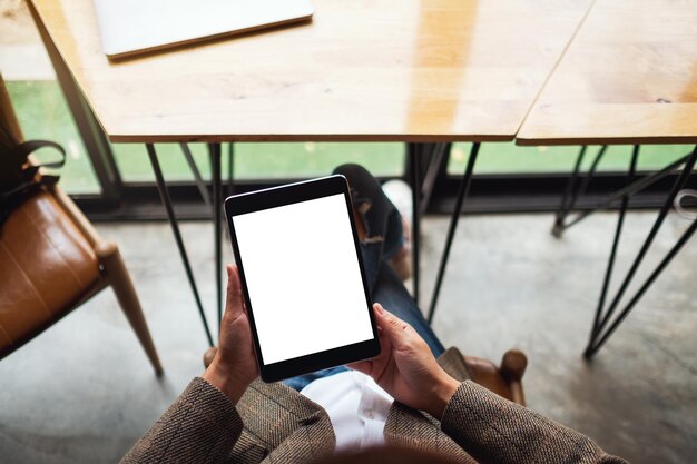 Image de maquette vue de dessus d'une femme assise et tenant un tablet pc noir avec un écran de bureau blanc vierge