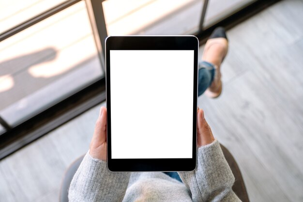 Image de maquette vue de dessus d'une femme tenant un tablet pc noir avec un écran blanc vierge