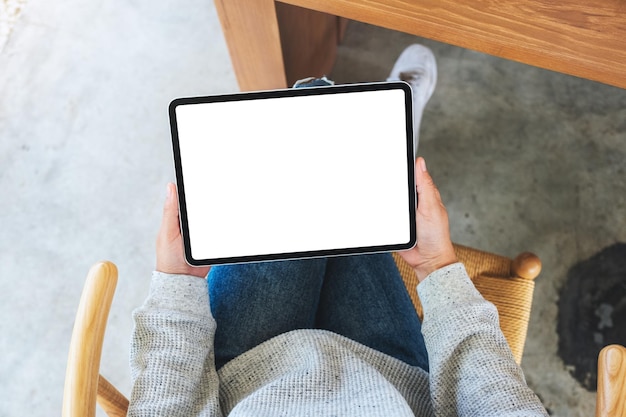 Image de maquette vue de dessus d'une femme tenant un tablet pc noir avec un écran de bureau blanc vierge