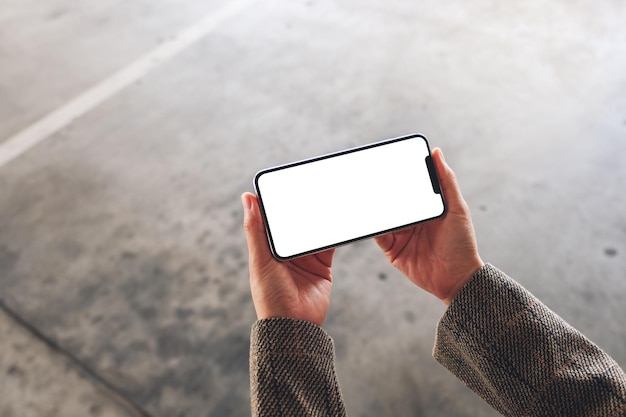 Image de maquette vue de dessus d'une femme tenant un téléphone portable avec un écran blanc vierge dans la rue