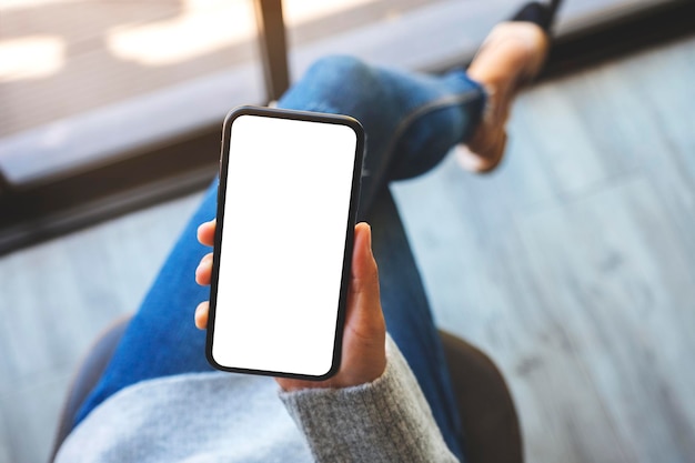 Image de maquette vue de dessus d'une femme tenant un téléphone portable avec un écran blanc vierge