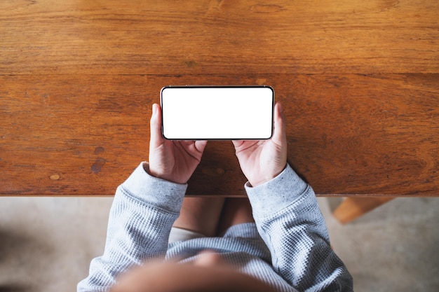 Image de maquette vue de dessus d'une femme tenant un téléphone portable avec un écran de bureau blanc vierge