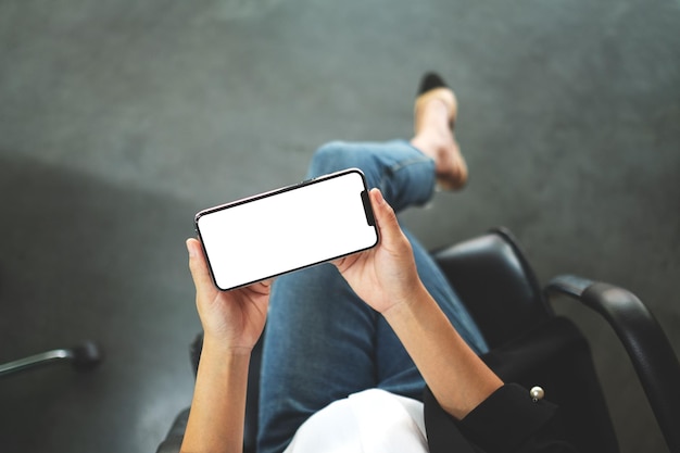 Image de maquette vue de dessus d'une femme tenant un téléphone portable noir avec un écran de bureau blanc vierge