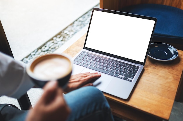 Image de maquette vue de dessus d'une femme utilisant et touchant le pavé tactile d'un ordinateur portable avec un écran de bureau blanc vierge tout en buvant du café