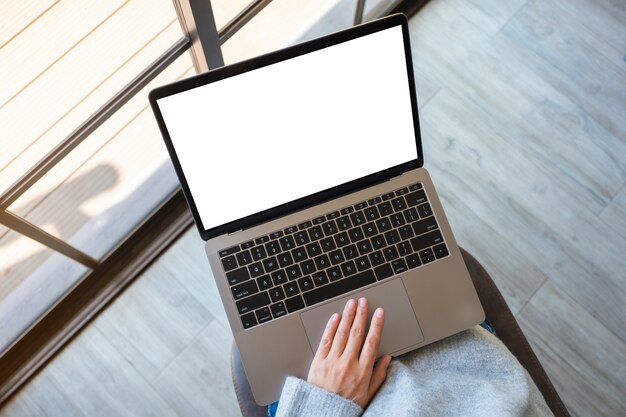 Image de maquette vue de dessus d'une femme utilisant et touchant le pavé tactile d'un ordinateur portable avec un écran de bureau blanc vierge