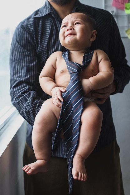 Image d'un mignon petit bébé portant une cravate dans les mains d'un jeune père Photo de nouveau-né de mignons petits enfants concep