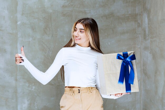 Image d'un modèle de fille avec une boîte présente montrant le pouce sur la pierre