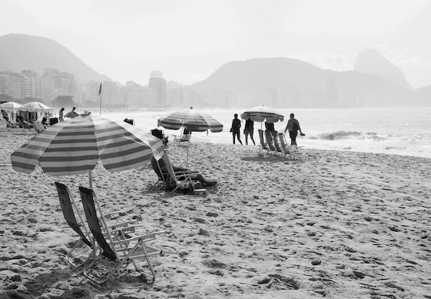 Image monochrome d'un groupe de personnes profitant des activités sur la plage de sable