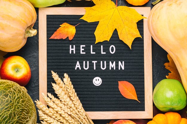 Image de nature morte d'automne avec melon, pommes, poires, seigle, citrouilles, feuillage coloré et tableau de lettres avec des mots Hello Autumn