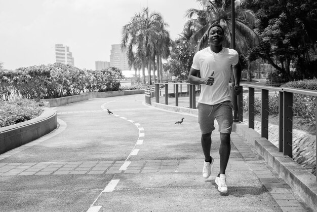 Image en noir et blanc du jeune homme africain qui court à l'extérieur dans le parc