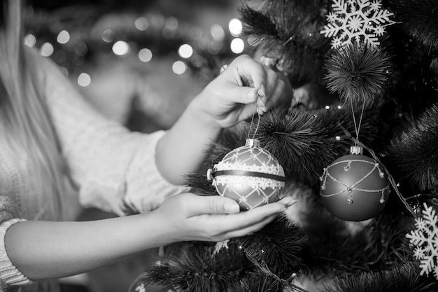 Image en noir et blanc de femme décorant l'arbre de Noël