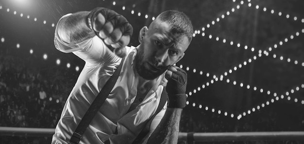 Image en noir et blanc d'un homme barbu en chemise blanche et bretelles dans le ring. Le concept de combats souterrains de poing. Technique mixte