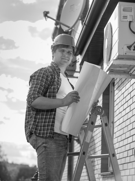 Image en noir et blanc d'un jeune technicien vérifiant le système de climatisation avec des instructions