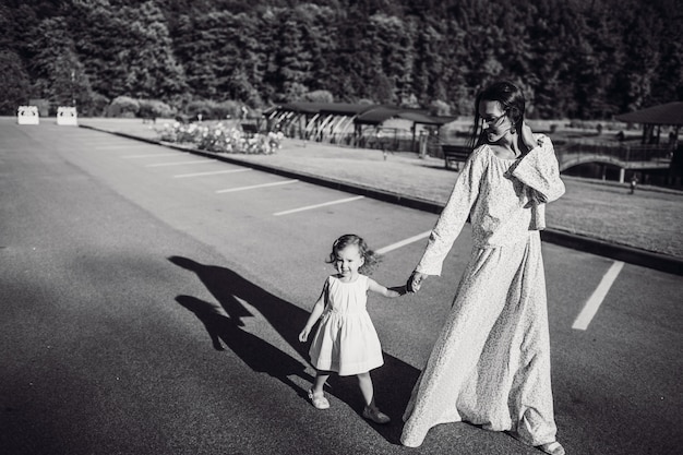 Image en noir et blanc de mère et fille qui se promènent dehors pendant le jour ensoleillé