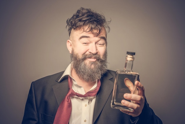 Image ondulée d'un homme barbu souriant échevelé en costume tenant dans sa main une bouteille d'alcool