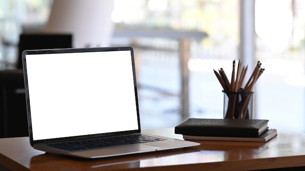 image d'un ordinateur tablette avec écran vide, papeterie et cahiers sur table en bois.
