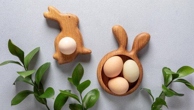 Photo image de pâques biologique des œufs dans des assiettes en bois comme lapin et carotte vert ruscus brindilles sur gris