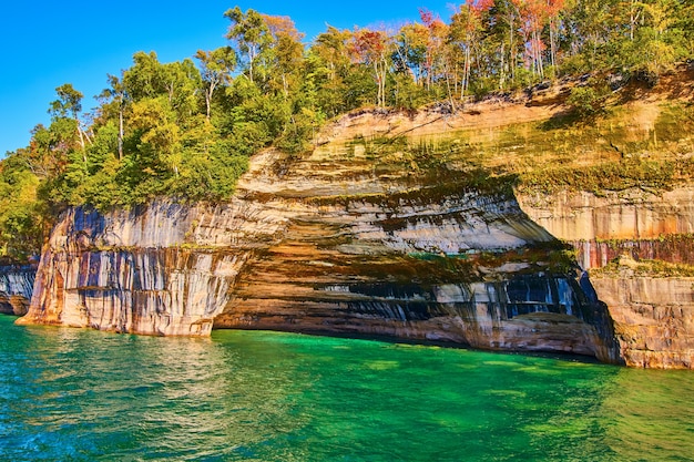 Image de Pictured Rocks avec des eaux turquoises et vertes autour d'un mur de falaise multicolore