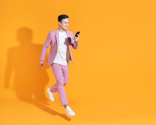 Image pleine longueur du jeune homme asiatique debout sur fond orange