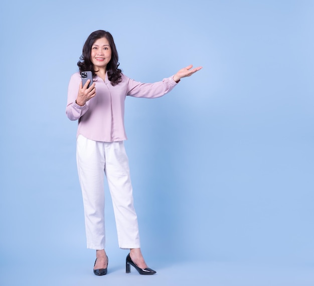 Image pleine longueur d'une femme asiatique d'âge moyen sur fond bleu