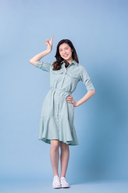 Image pleine longueur d'une jeune femme asiatique portant une robe sur fond bleu