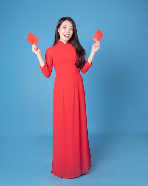 Image pleine longueur d'une jeune femme vietnamienne portant un ao dai rouge sur fond