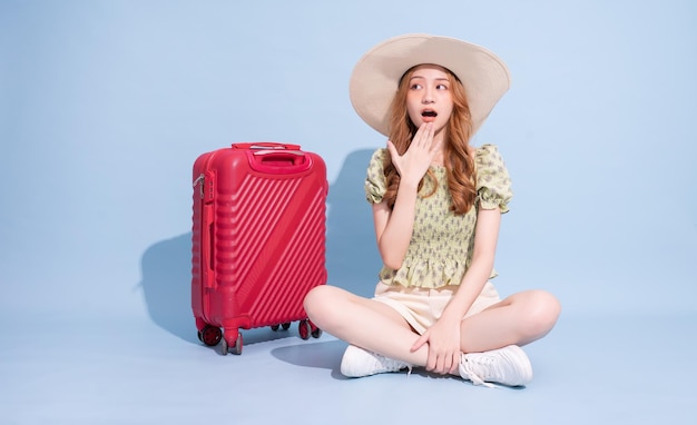 Image pleine longueur de jeune fille asiatique avec valise sur fond bleu concept de voyage