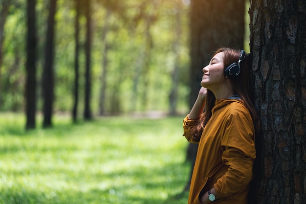 Image de portrait d'une belle jeune femme asiatique aime écouter de la musique avec un casque dans le parc