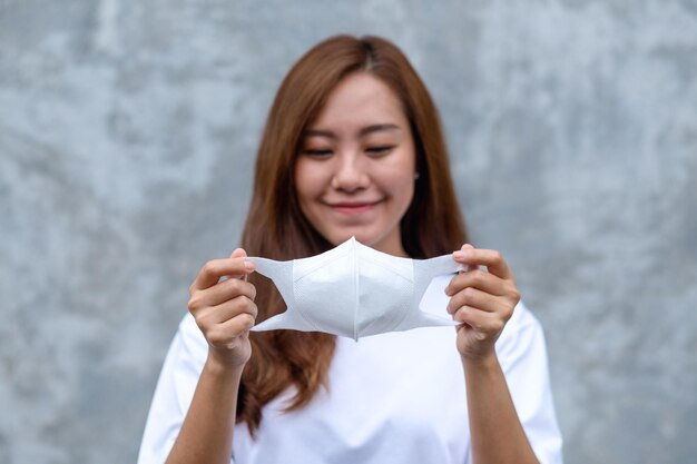 Image de portrait d'une femme asiatique tenant et mettant un masque protecteur pour le concept de soins de santé et Covid19