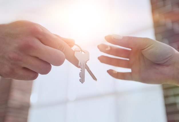 Image recadrée de l'agent immobilier donnant les clés de la maison à l'homme au bureau