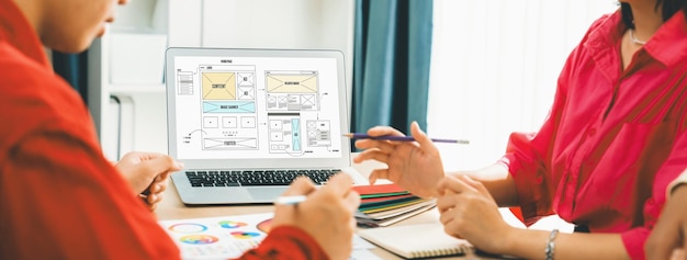 Photo l'image recadrée d'un architecte d'intérieur présente la couleur à partir d'échantillons de couleurs tandis que l'ordinateur portable affiche des conceptions filaires de site web pour l'application mobile et le site web. conception créative et concept commercial panaché