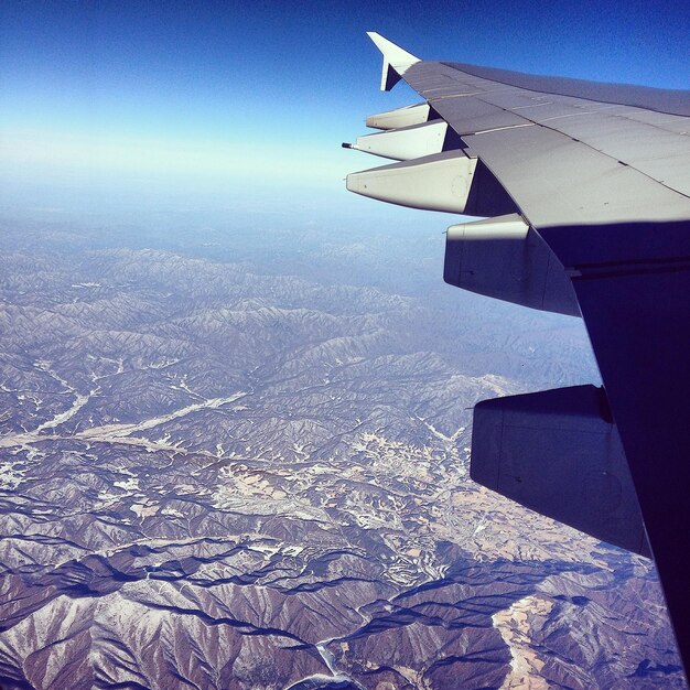 Photo image recadrée d'un avion volant au-dessus des montagnes