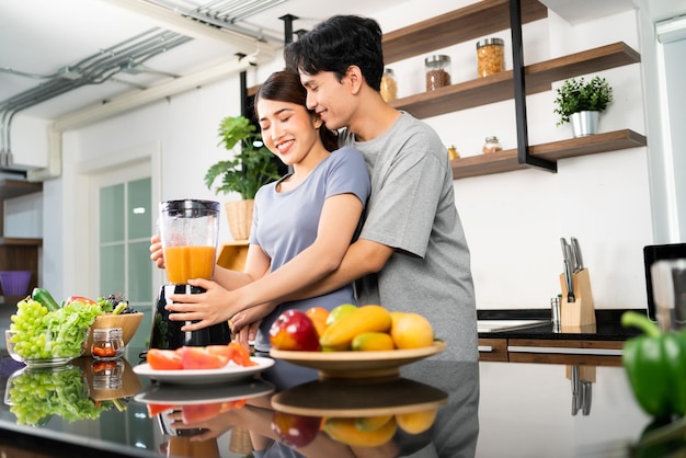 Image recadrée d'un couple asiatique heureux qui aime utiliser un mixeur pour préparer un smoothie végétalien sain sur le comptoir de la cuisine Couple faisant un smoothie végétalien ensemble à la maison pour un mode de vie sain