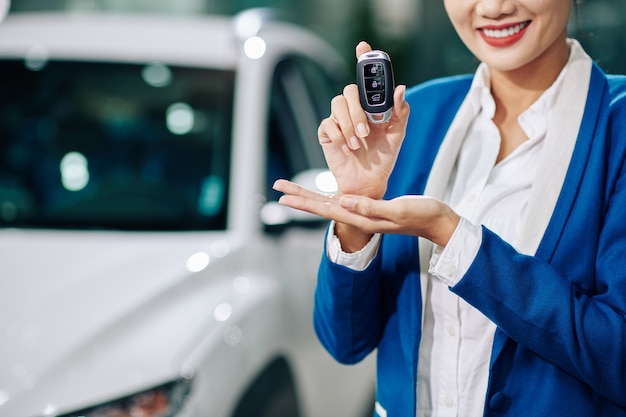 Image recadrée d'un directeur de concession automobile souriant montrant des clés électroniques